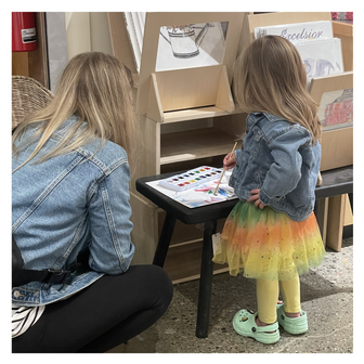 Woman and child painting with watercolor at a small table with art supplies in an Ann Arbor store.