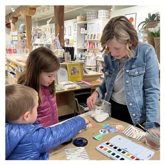 Artist Emily Frushour painting with children during a watercolor workshop at a gift shop.