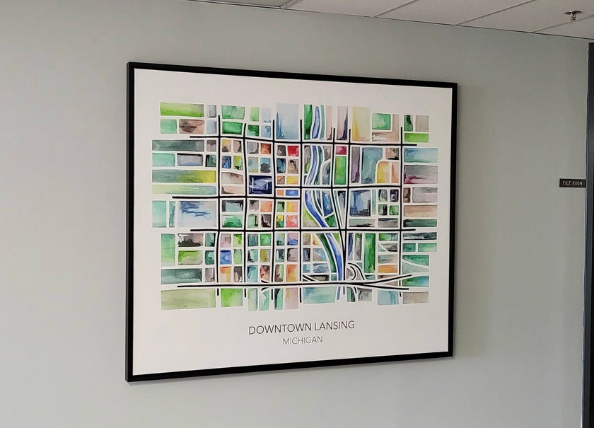 Large framed watercolor map of downtown Lansing. The map is bright and geometric and hanging in an office.