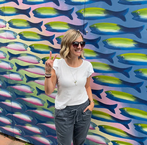 Artist Emily Frushour standing in front of fish mural in Leland, Michigan.