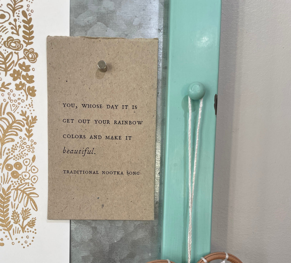 Handmade card with a rainbow quote hanging on wall in artist studio.