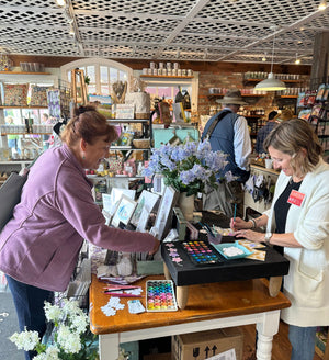 Artist Emily Frushour painting and visiting with customer during the Lilac Festival on Mackinac Island.