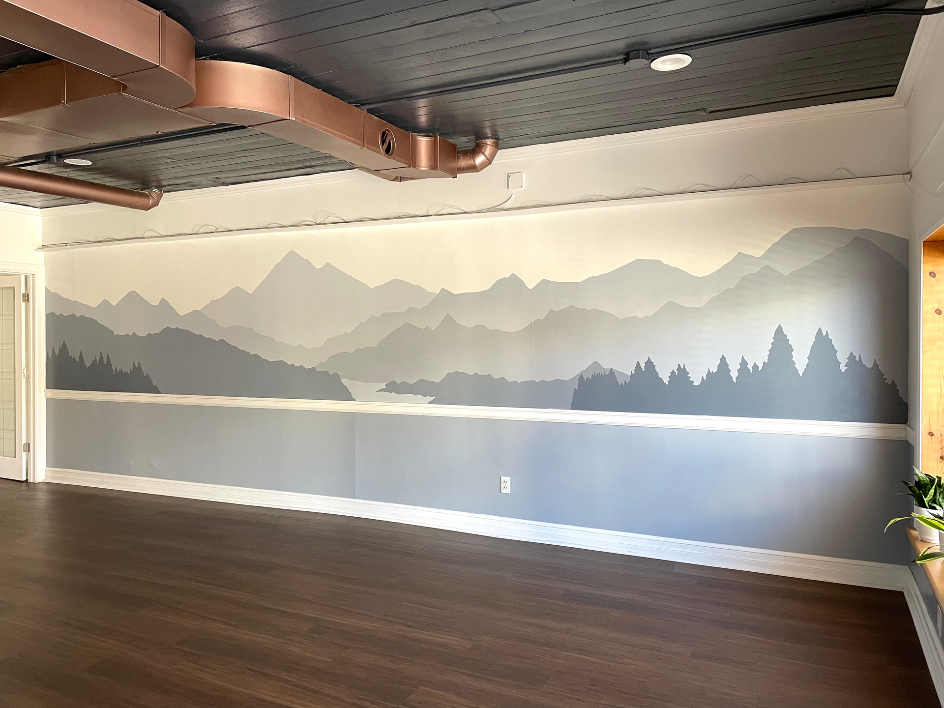 Large mural for yoga studio showing mountains and a forest in shades of gray. Artwork by Emily Frushour.