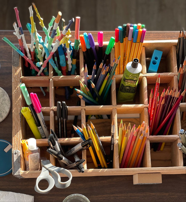 Variety of art supplies in artist Emily Frushour's studio, including pencils, markers, scissors and pens.