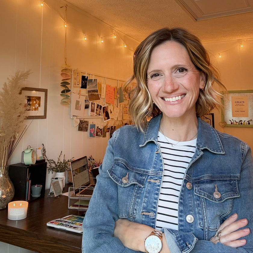 Artist Emily Frushour standing with arms crossed in her art studio in Lansing, Michigan.