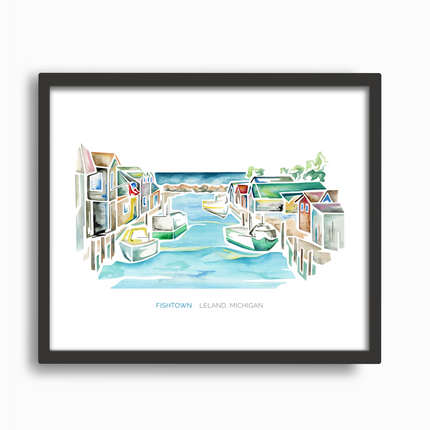 Framed watercolor of a scene in Fishtown, Leland, Michigan, featuring a dam, tugboats and fishing shanties. Colorful artwork in a black frame.