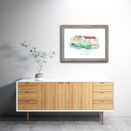 Framed watercolor painting of a green tugboat named Joy in the village of Fishtown in Leland, Michigan, hanging in a home.