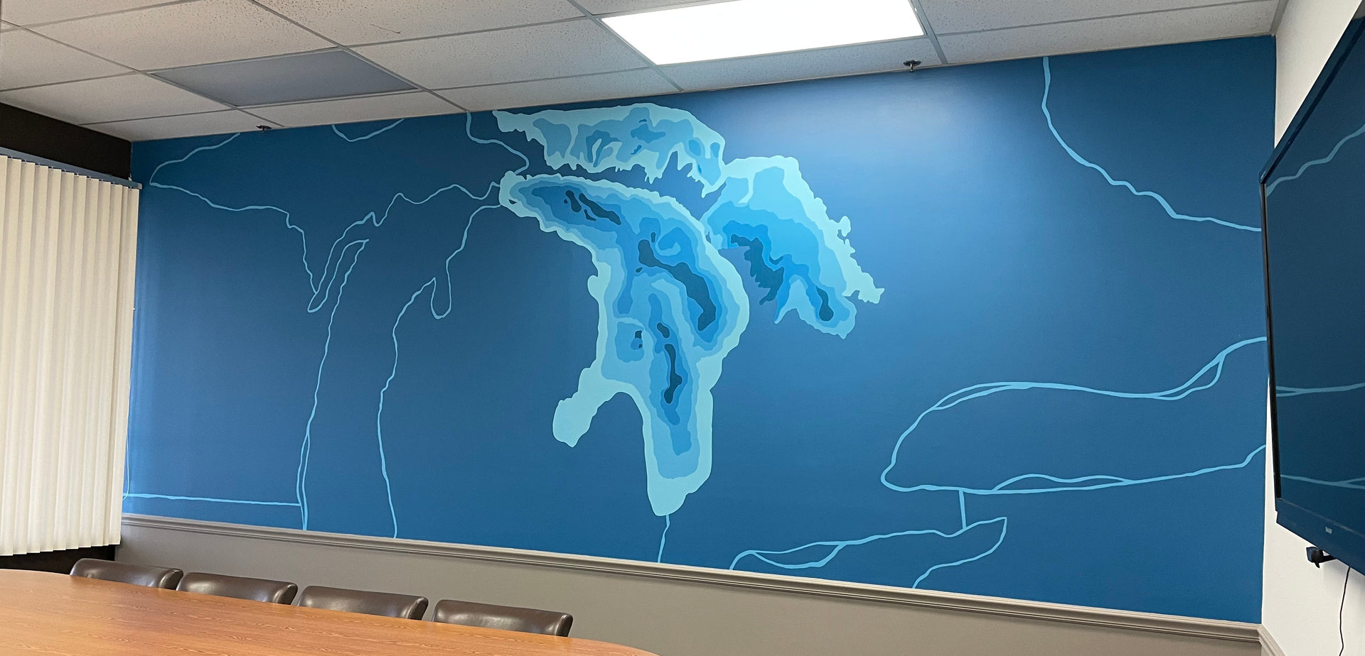 Vibrant office mural of Lake Huron and Michigan, painted in shades of blue by artist Emily Frushour.