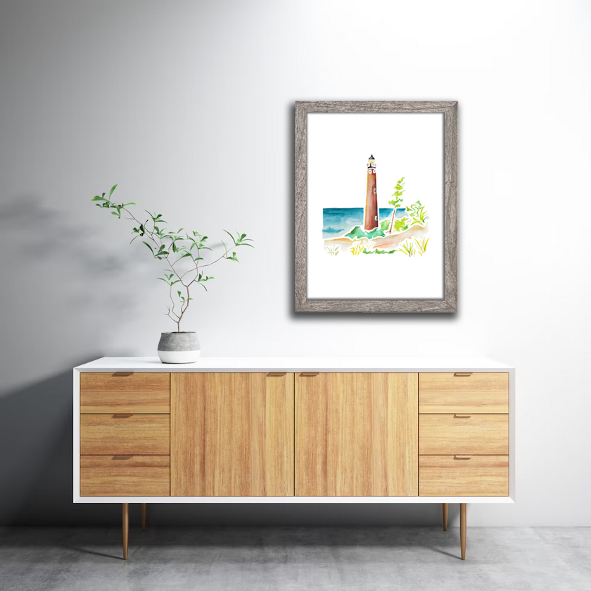 Gray frame wtih watercolor painting of Little Sable Point Lighthouse on Lake Michigan, surrounded by sand dunes and grass.