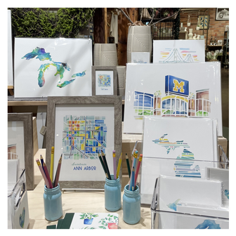 Collection of Michigan-themed watercolor artwork by Emily Frushour, on display at a store in Ann Arbor.