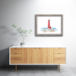 Gray frame with bright watercolor painting of the Muskegon lighthouse in vibrant red, with stone pier and Lake Michigan.