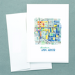 Folded notecard with a watercolor painting showing a colorful and geometric map of downtown Ann Arbor, Michigan.