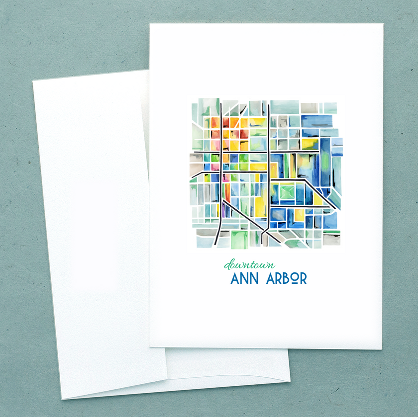 Folded notecard with a watercolor painting showing a colorful and geometric map of downtown Ann Arbor, Michigan.