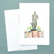 Folded white notecard with watercolor of spartan statue in bronze and green, with envelope.