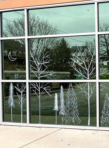 Delicate winter window art illustration of a forest with snowflakes and moon, created by artist Emily Frushour.