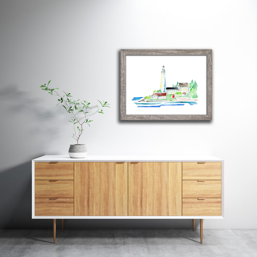 Watercolor print of the lighthouse on South Manitou Island in northern Michigan, surrounded by trees and Lake Michigan. Hanging in a gray frame on a wall.