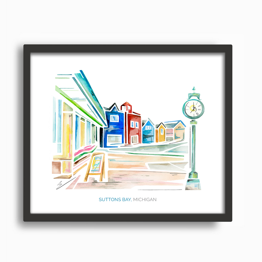 Black frame with a bright and colorful watercolor painting of a street scene in Suttons Bay, Michigan, showing shops and a clock tower.