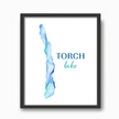 Vibrant blue watercolor print of Torch Lake in Michigan, in a black frame.