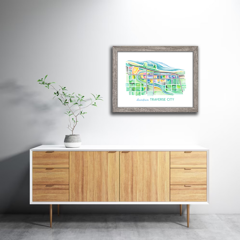 Framed bright and colorful watercolor painting showing a map of Traverse City, Michigan, in vibrant greens and blues.