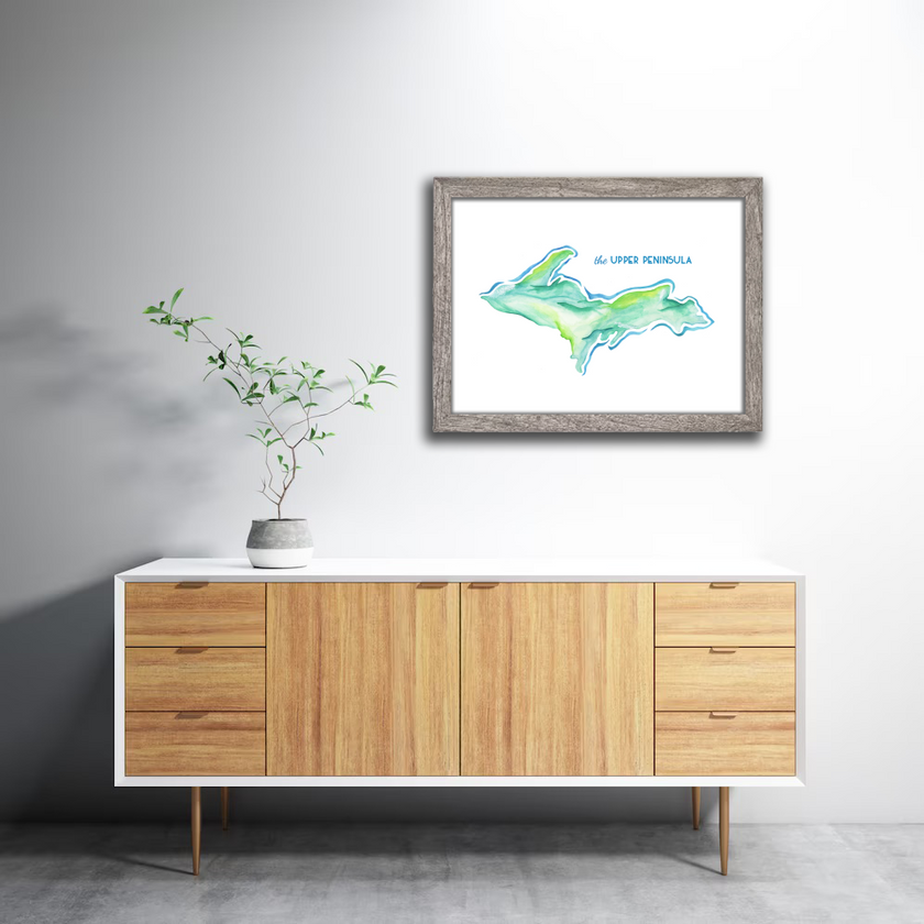 Watercolor painting of a map of Michigan's upper peninsula, created in shades of green and blue, placed in a gray frame.