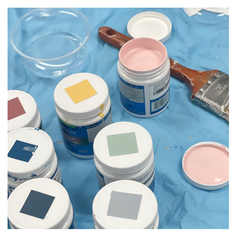 Jars of paint and paint swatches on a dropcloth for a mural by Emily Frushour.