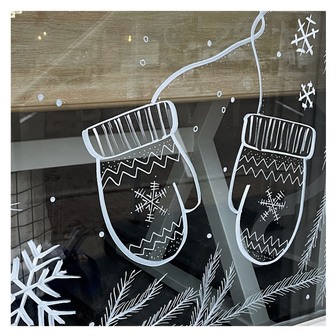 Delicate window art illustration showing pine branches, snowflakes and winter mittens, created by artist Emily Frushour.